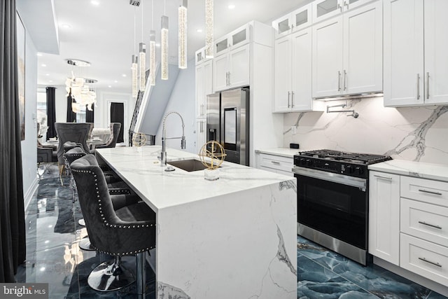 kitchen featuring light stone countertops, an island with sink, stainless steel appliances, and white cabinetry