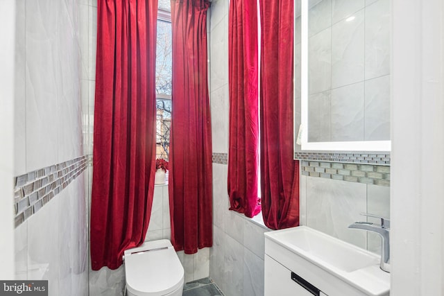 bathroom featuring tile walls, toilet, and vanity