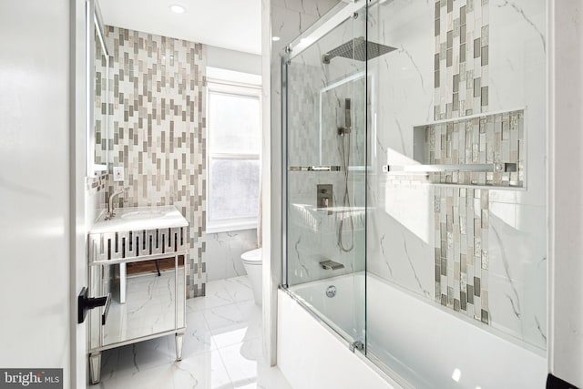 full bathroom featuring tile walls, toilet, vanity, and shower / bath combination with glass door