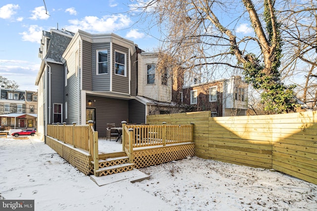 snow covered rear of property with a wooden deck