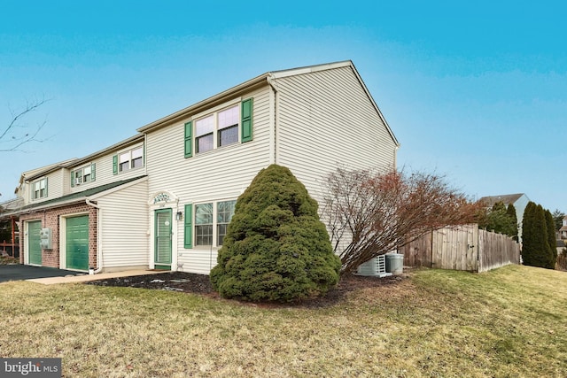 exterior space with a garage, a lawn, and central AC