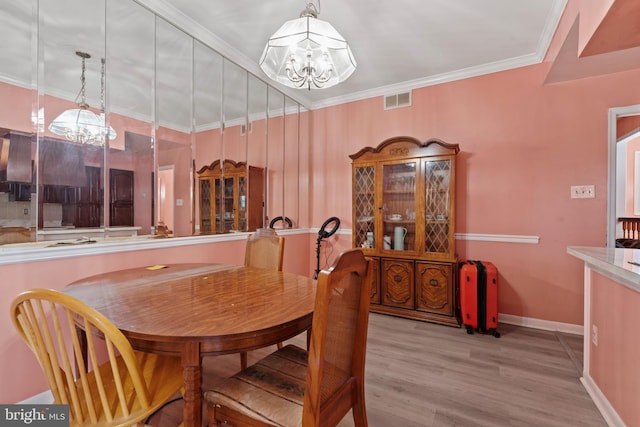 dining room with light wood-type flooring, crown molding, and a chandelier