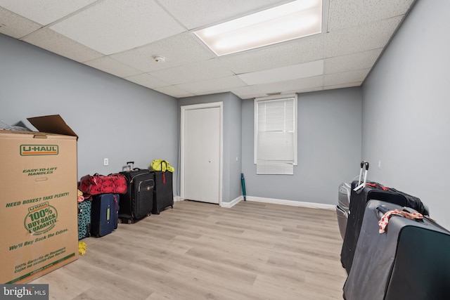 basement featuring a drop ceiling and light hardwood / wood-style flooring