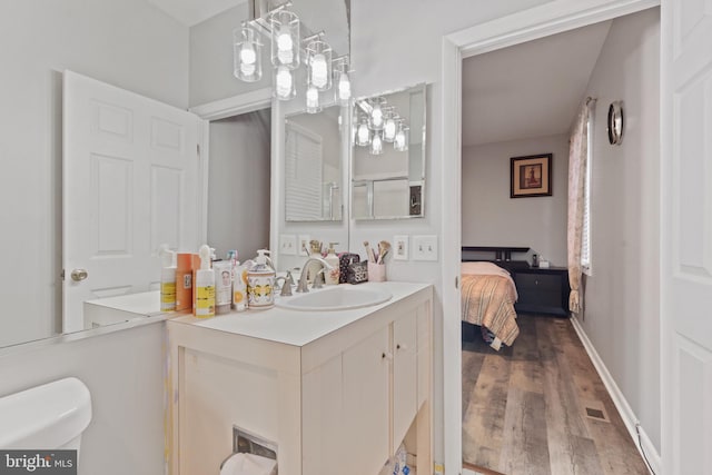 bathroom with toilet, vanity, and hardwood / wood-style floors