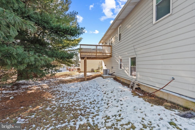 yard covered in snow featuring a deck and central air condition unit