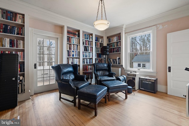 living area featuring crown molding, a healthy amount of sunlight, and light wood-type flooring