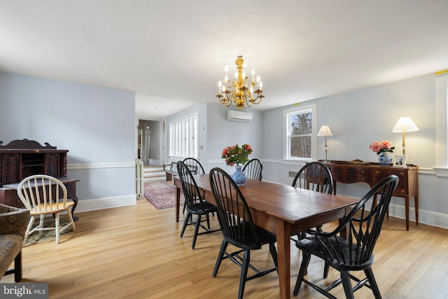 dining space featuring a notable chandelier, light hardwood / wood-style flooring, an AC wall unit, and a healthy amount of sunlight