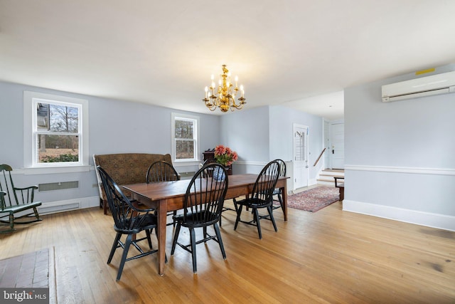 dining area featuring an inviting chandelier, light hardwood / wood-style flooring, and an AC wall unit