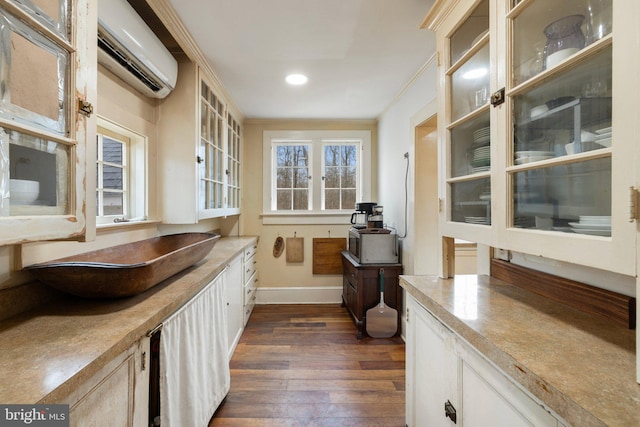 kitchen featuring dark hardwood / wood-style flooring, ornamental molding, and an AC wall unit