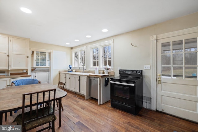 kitchen featuring sink, white cabinetry, light wood-type flooring, stainless steel dishwasher, and black range with electric stovetop