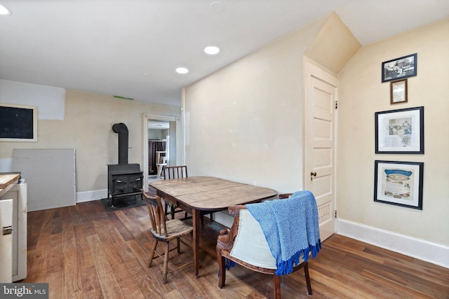 dining space with a wood stove and dark wood-type flooring