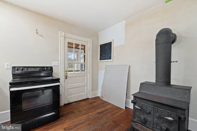 kitchen with black / electric stove, dark hardwood / wood-style floors, and a wood stove