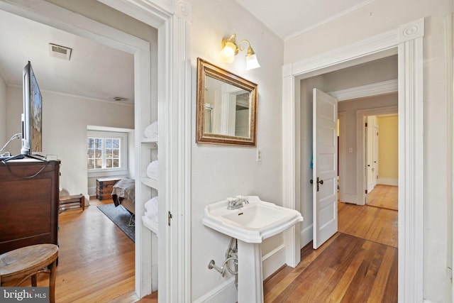 bathroom featuring hardwood / wood-style flooring, crown molding, and sink