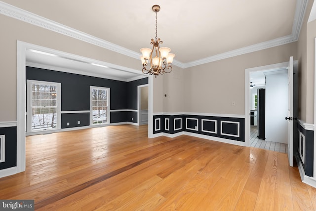 interior space featuring light wood-type flooring, ceiling fan with notable chandelier, and ornamental molding