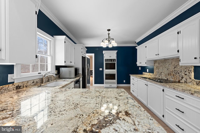 kitchen featuring decorative light fixtures, sink, white cabinets, decorative backsplash, and stainless steel appliances