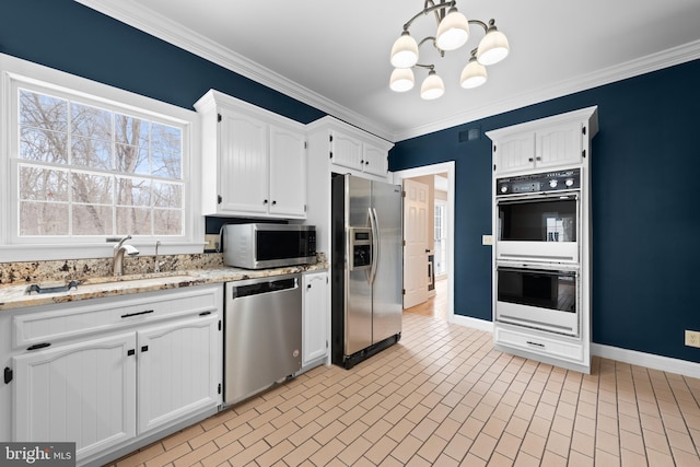 kitchen with appliances with stainless steel finishes, decorative light fixtures, white cabinets, light stone counters, and ornamental molding