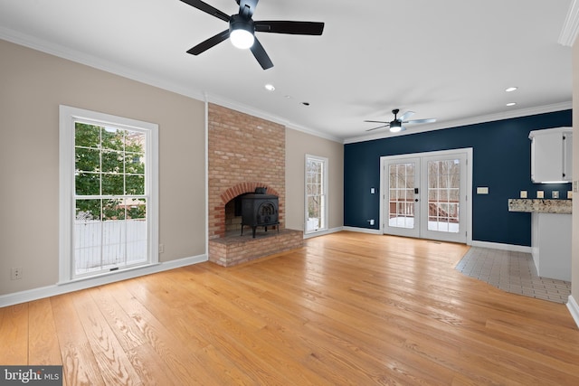 unfurnished living room with a wood stove, french doors, ceiling fan, and crown molding