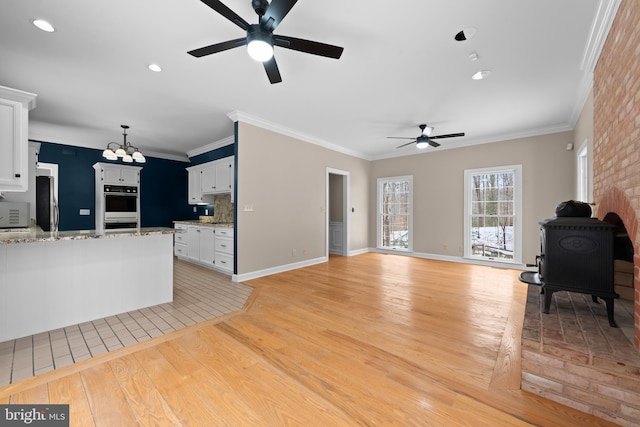 living room featuring ceiling fan with notable chandelier, ornamental molding, and light hardwood / wood-style floors