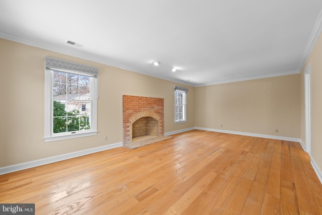 unfurnished living room featuring a wealth of natural light, ornamental molding, light hardwood / wood-style floors, and a fireplace