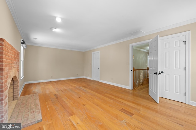 unfurnished living room featuring hardwood / wood-style flooring, a brick fireplace, and ornamental molding