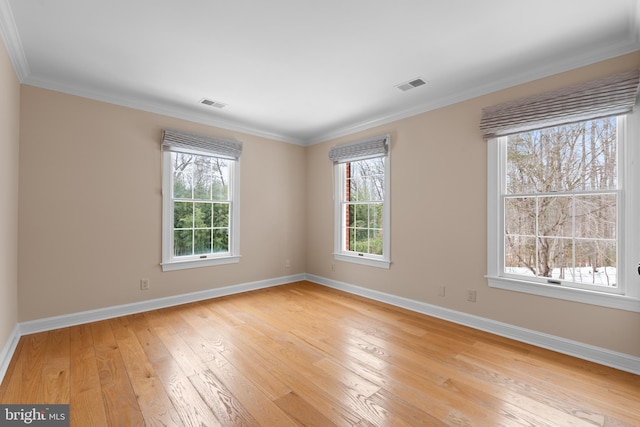 spare room with light hardwood / wood-style flooring, a wealth of natural light, and ornamental molding