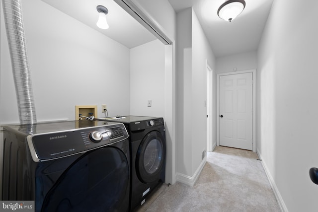 clothes washing area with light colored carpet and separate washer and dryer