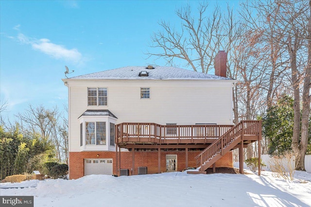 snow covered house featuring a garage, a wooden deck, and central AC