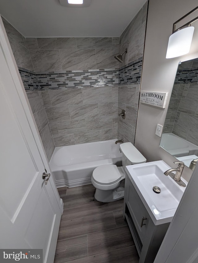 full bathroom featuring toilet, vanity, hardwood / wood-style floors, and tiled shower / bath