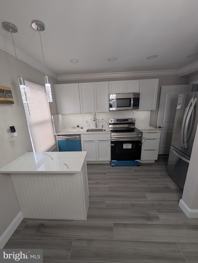 kitchen with pendant lighting, kitchen peninsula, sink, appliances with stainless steel finishes, and white cabinets