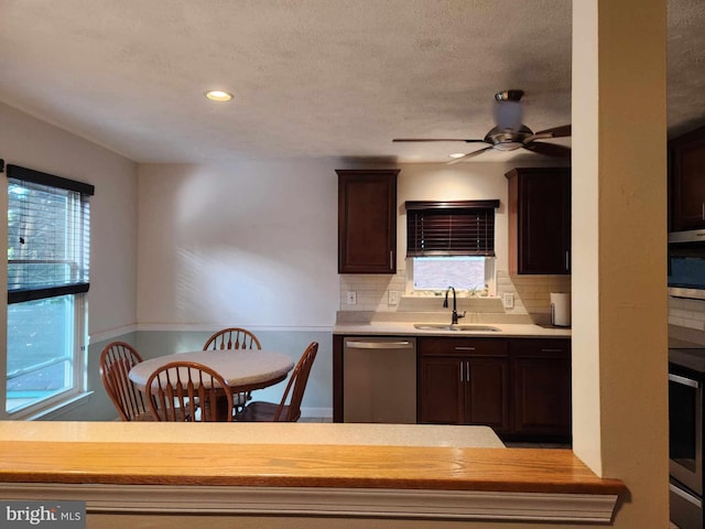 kitchen with appliances with stainless steel finishes, sink, dark brown cabinets, and a wealth of natural light