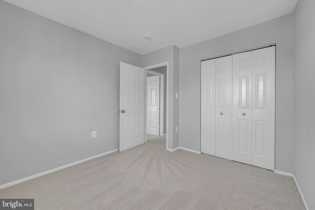 unfurnished bedroom with light colored carpet and a closet