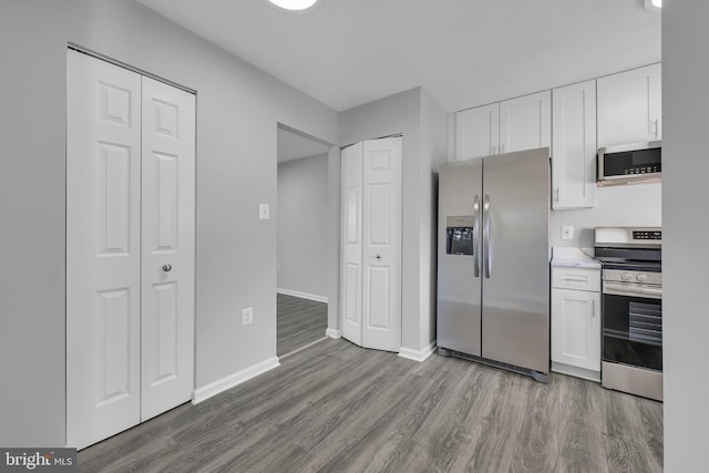 kitchen featuring light wood-type flooring, stainless steel appliances, and white cabinetry