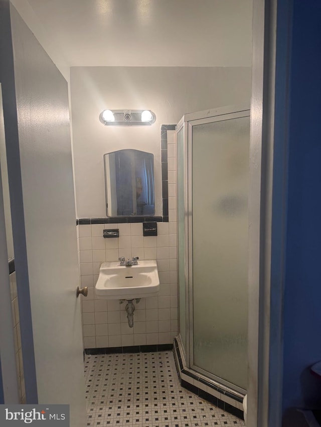 bathroom featuring a stall shower, tile walls, and a sink