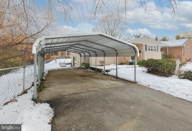 snow covered parking area with a carport