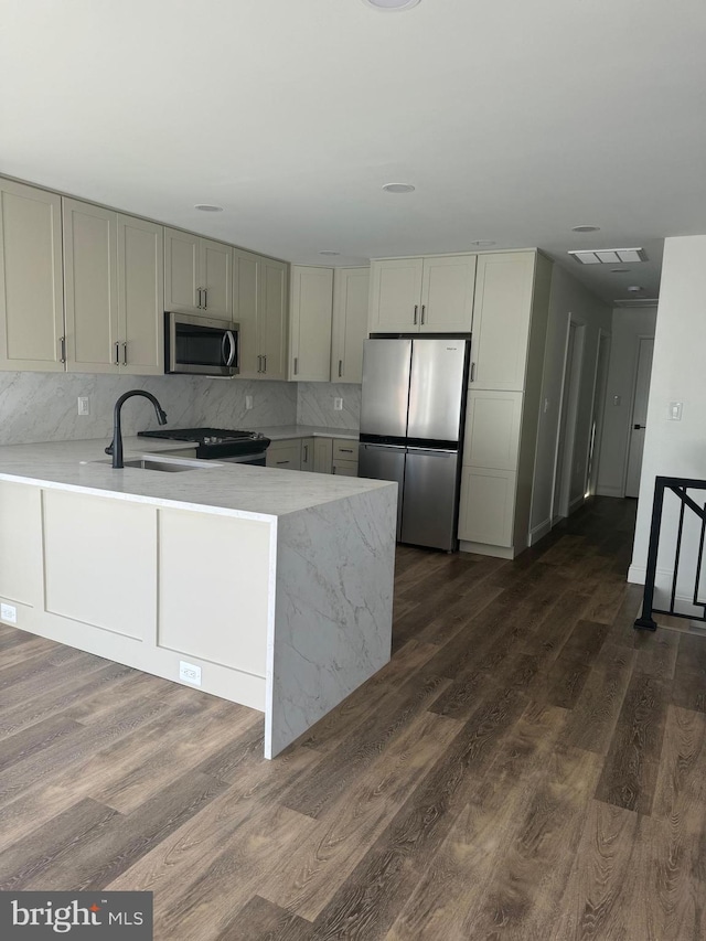 kitchen featuring kitchen peninsula, appliances with stainless steel finishes, and dark hardwood / wood-style flooring