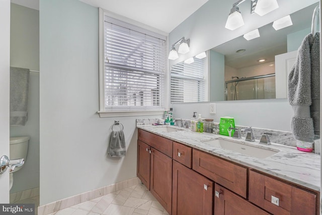 full bath with double vanity, a stall shower, baseboards, and a sink