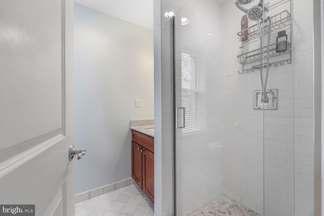 full bathroom with marble finish floor, a stall shower, vanity, and baseboards