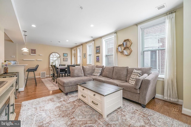 living area with recessed lighting, visible vents, light wood-style flooring, and baseboards