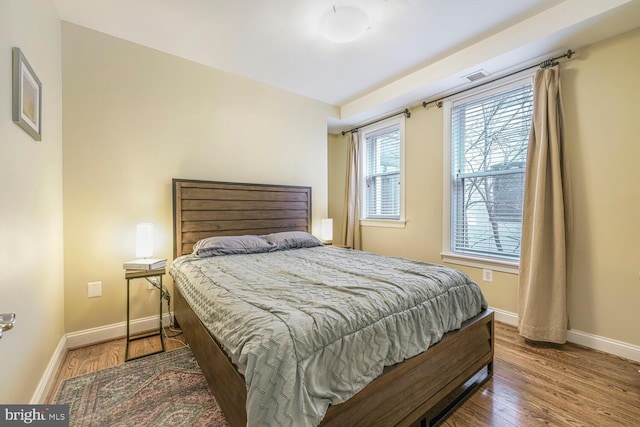 bedroom with visible vents, baseboards, and wood finished floors