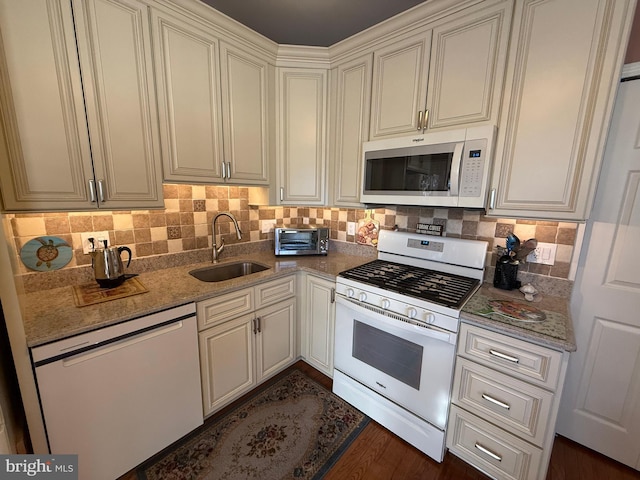 kitchen featuring sink, light stone counters, tasteful backsplash, dark hardwood / wood-style flooring, and white appliances