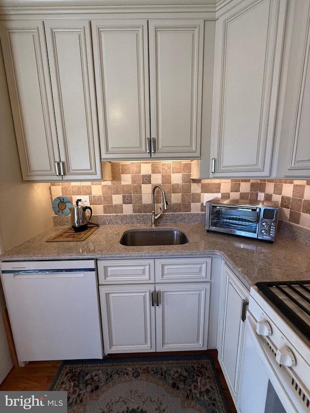 kitchen with sink, white appliances, white cabinetry, backsplash, and light stone counters