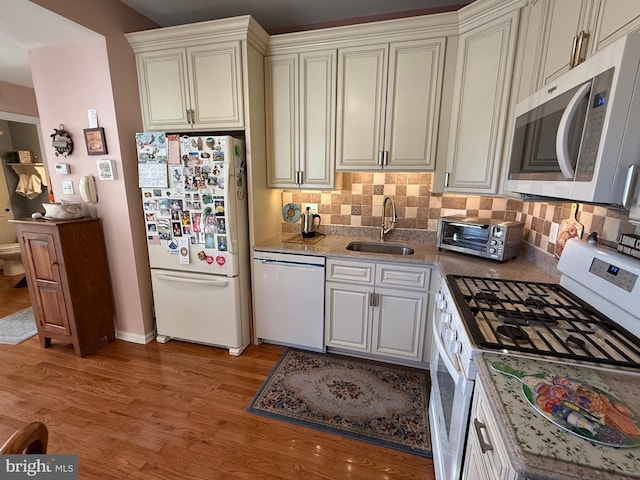 kitchen featuring tasteful backsplash, sink, white appliances, and light wood-type flooring