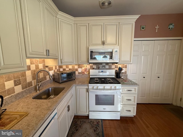 kitchen with tasteful backsplash, sink, stainless steel dishwasher, white gas range oven, and light stone countertops