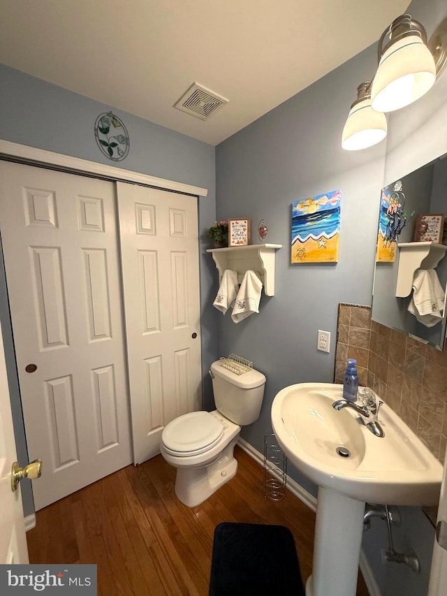 bathroom featuring tasteful backsplash, hardwood / wood-style flooring, and toilet