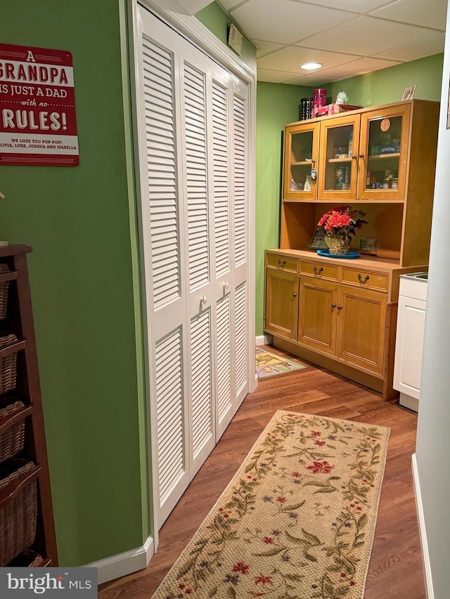 hallway with light hardwood / wood-style flooring and a paneled ceiling