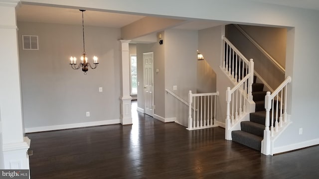 foyer entrance with a notable chandelier, dark hardwood / wood-style flooring, and decorative columns