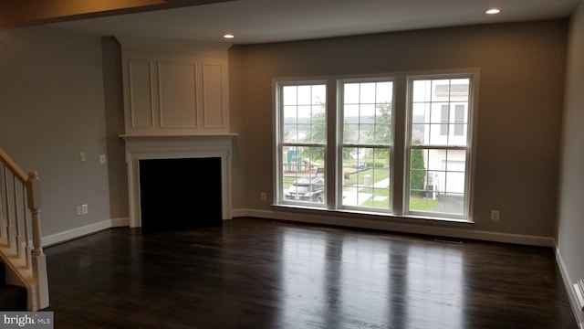 unfurnished living room featuring a large fireplace and dark hardwood / wood-style floors