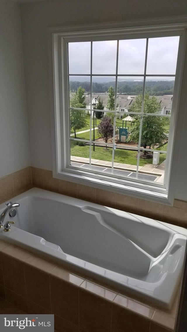 bathroom featuring a wealth of natural light and tiled tub