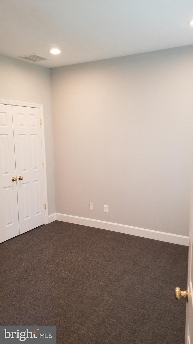 spare room featuring dark colored carpet