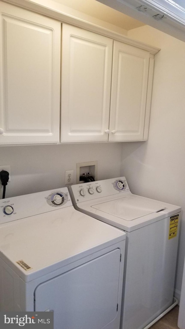 clothes washing area with washer and clothes dryer and cabinets